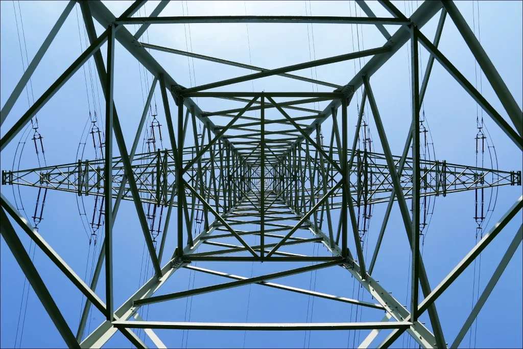 Blick von unten durch einen Hochspannungsmast in den blauen Himmel