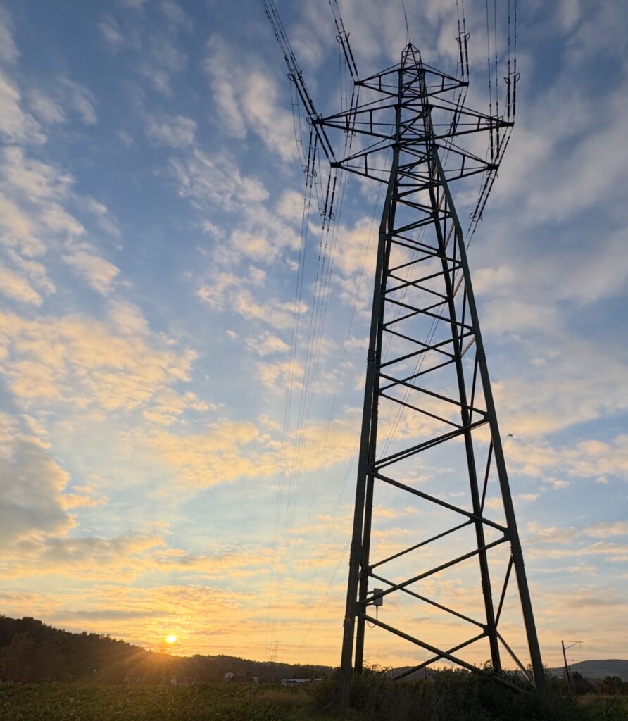 Blick von unten durch einen Hochspannungsmast in den Sonnenuntergang